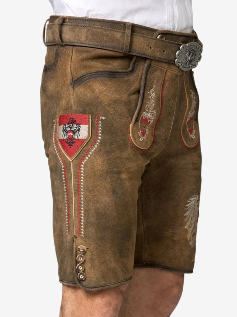Side view of brown lederhosen with red embroidery, decorative stitching, and traditional crest detail on the thigh.
