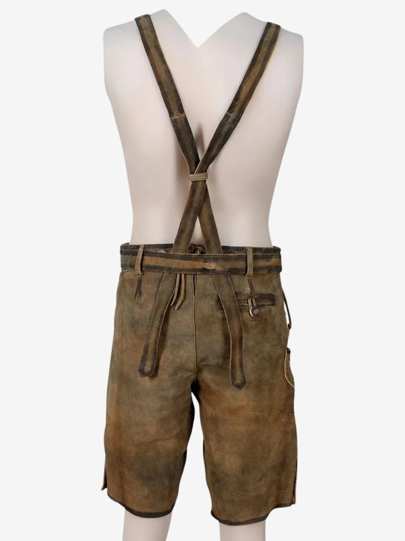 Back view of brown leather lederhosen with suspenders on a mannequin, featuring crossed straps and adjustable waistband.