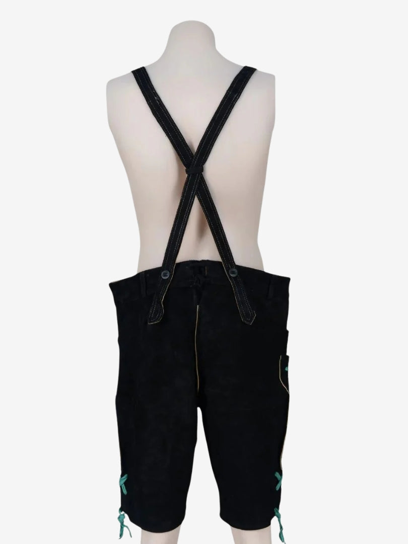 Back view of black lederhosen with suspenders on a mannequin, featuring crossed straps and knee-length design.