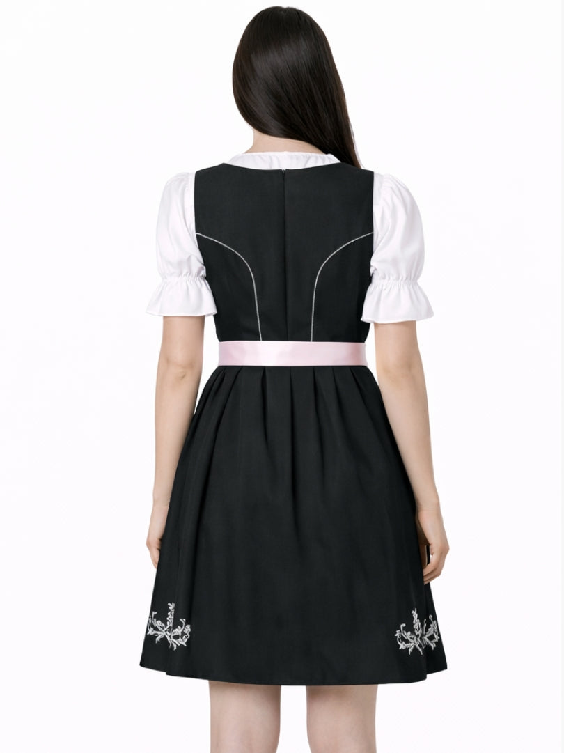 Front view of women's black Bavarian dirndl dress with white blouse, pink lace-up bodice, and pink apron in traditional Oktoberfest style.