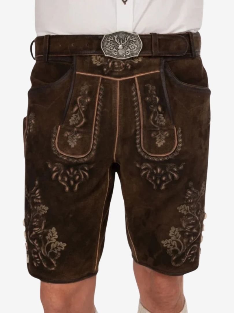 Dark brown leather lederhosen shorts with detailed embroidery on the front panel, worn with a white shirt and a decorative belt with a metal buckle.