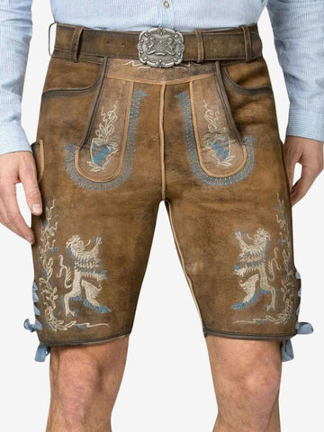 Close-up of brown suede lederhosen with blue and white embroidery, featuring lion motifs, decorative front flap, and a metal belt buckle.