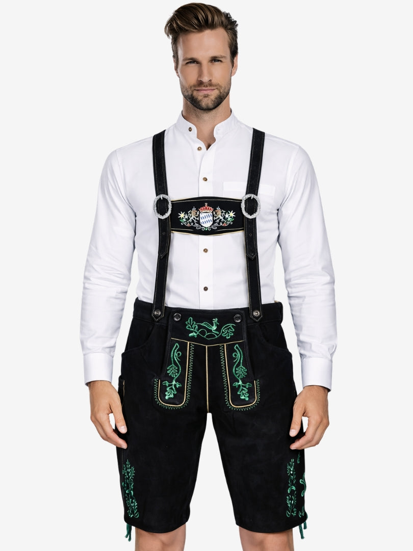 Man wearing black lederhosen with green embroidery and suspenders, paired with a white shirt.