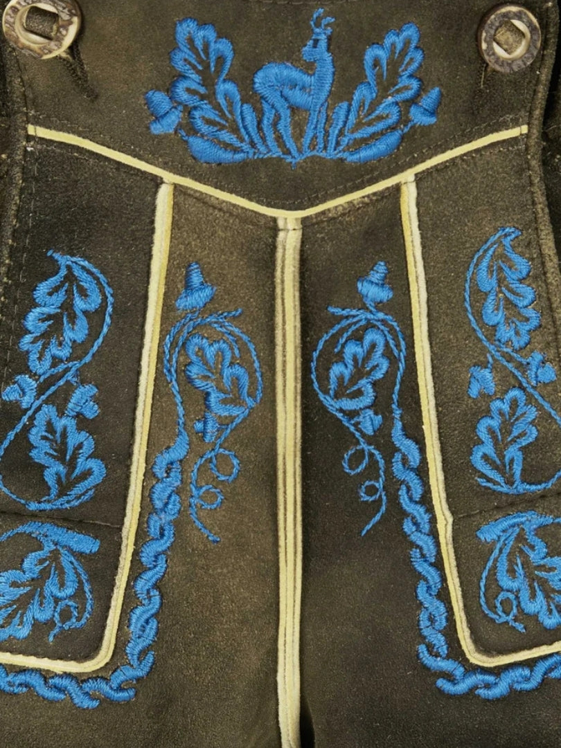Man wearing dark brown lederhosen with vibrant blue embroidery paired with a white shirt in traditional Bavarian style.