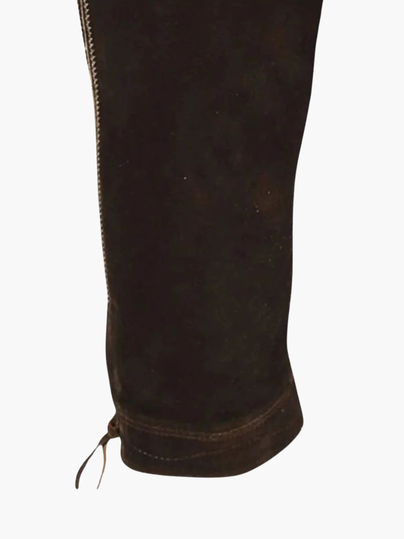Close-up of brown leather bundhosen leg hem featuring folded cuff, stitching detail, and adjustable lace-up fastening.