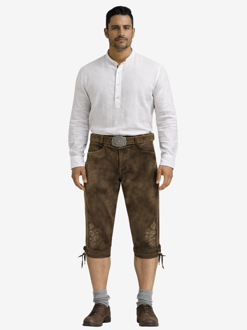 Man wearing brown leather bundhosen with a white shirt, grey socks, and brown shoes in a full-length front view.