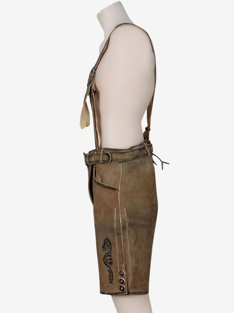 Side profile of brown lederhosen with suspenders, showing stitched patterns, side pocket, and button detailing on the leg.