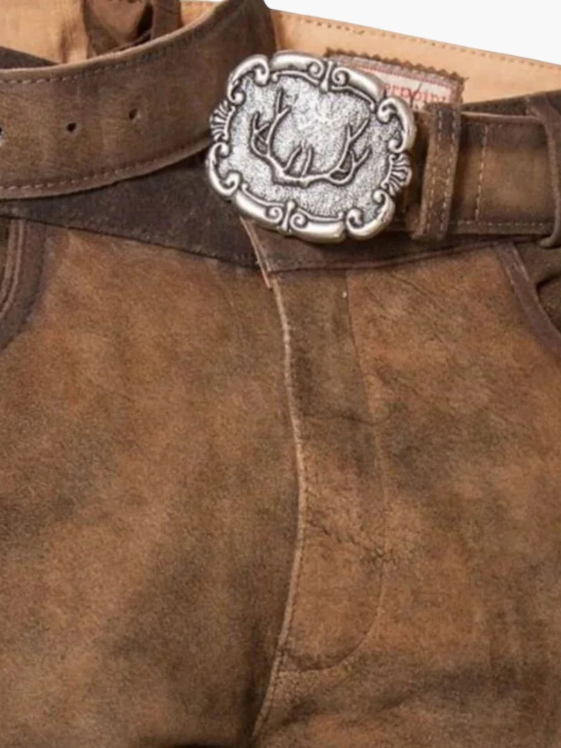 Close-up of brown suede bundhosen waistband featuring a traditional metal buckle with deer motif and rustic leather texture.