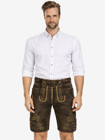 Man wearing dark brown leather lederhosen with subtle green embroidery, paired with a white button-down shirt in a traditional Bavarian style.