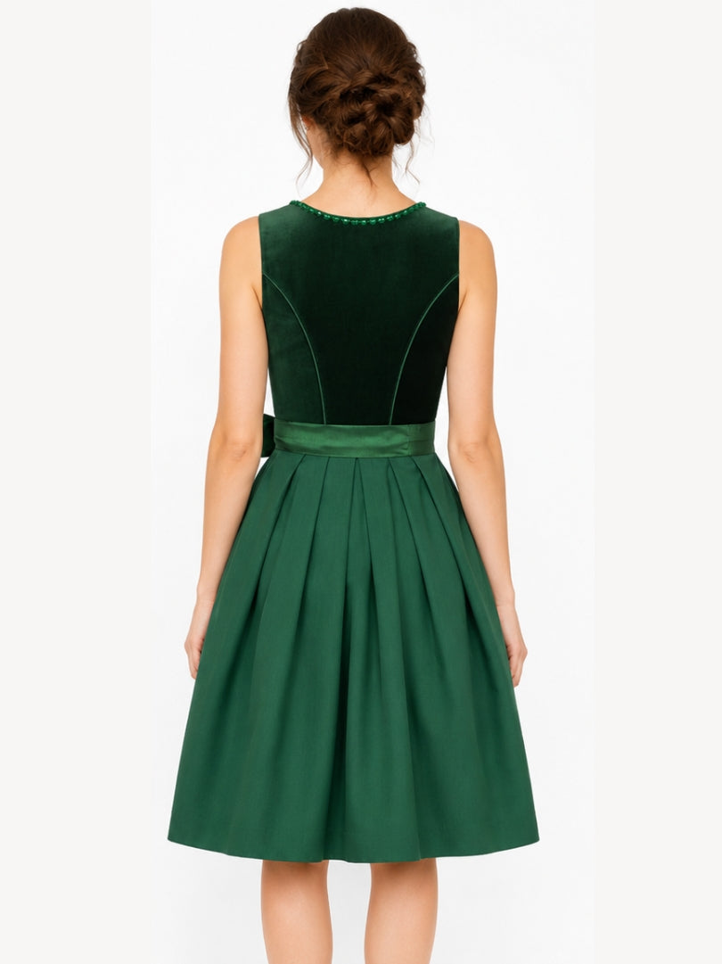 A woman shown from the back wearing a sleeveless emerald green dress with a velvet-like structured bodice and a pleated skirt, against a plain light background.