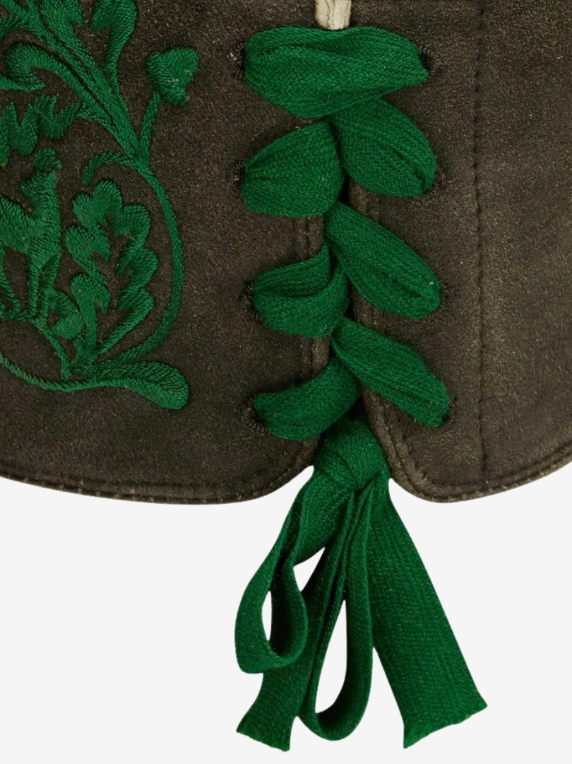 Close-up of side lace-up detail with green ties and embroidered pattern on leather lederhosen.