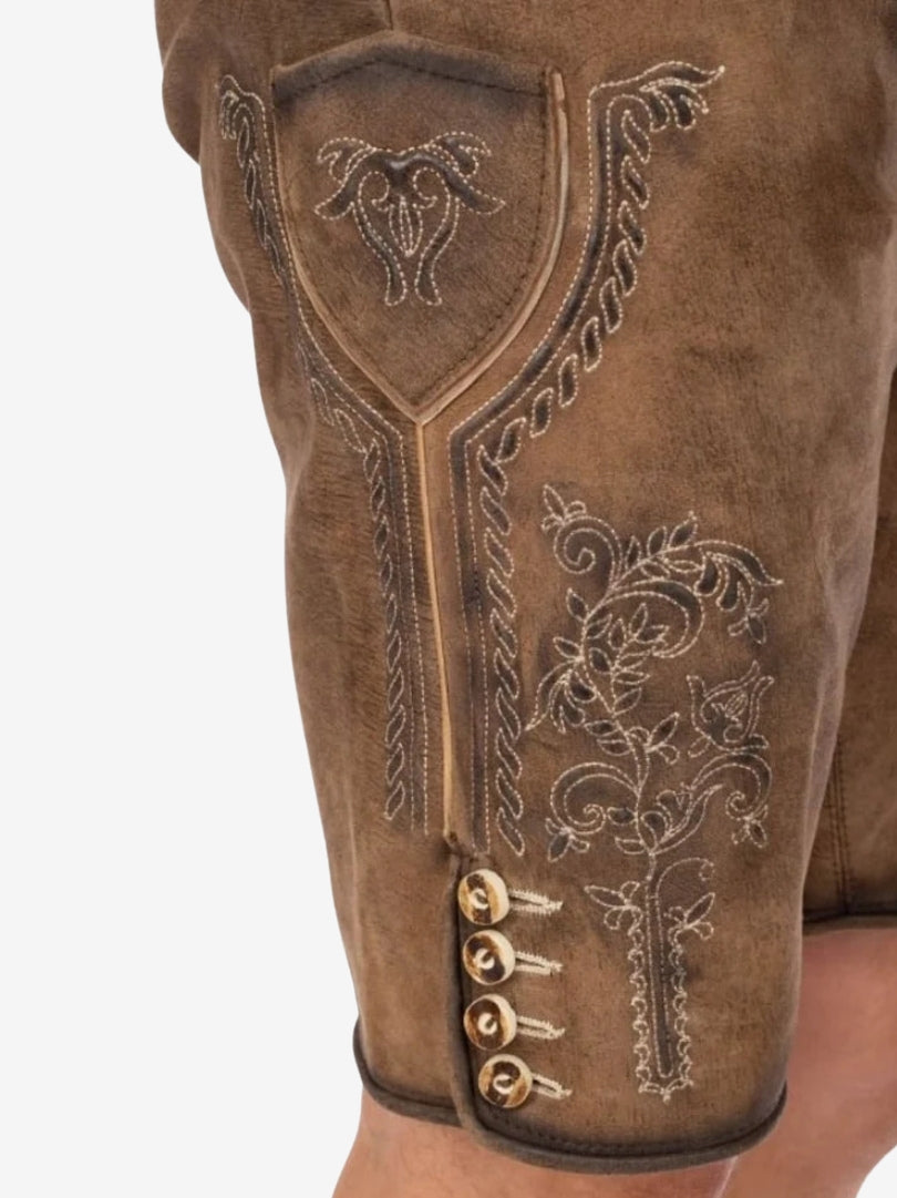 Detailed close-up of embroidered design on brown leather lederhosen with traditional buttons on the side.