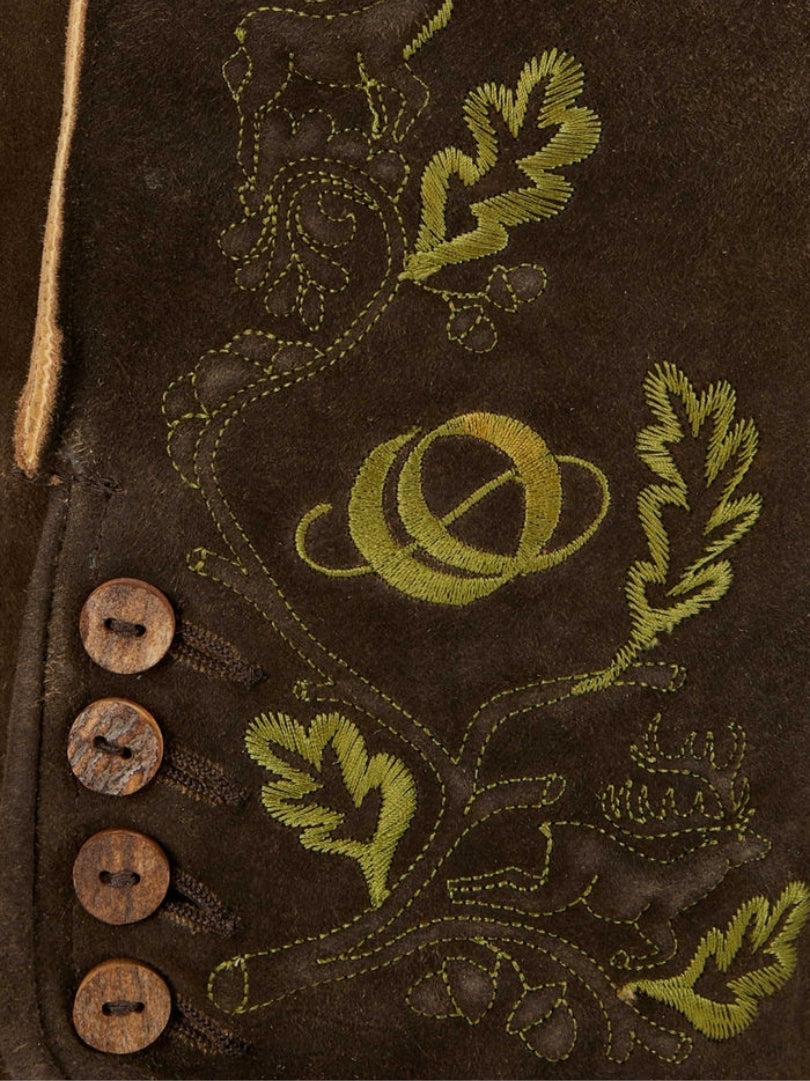 Close-up of green embroidered design on brown leather lederhosen featuring leaves, a deer motif, and decorative stitching with side buttons.