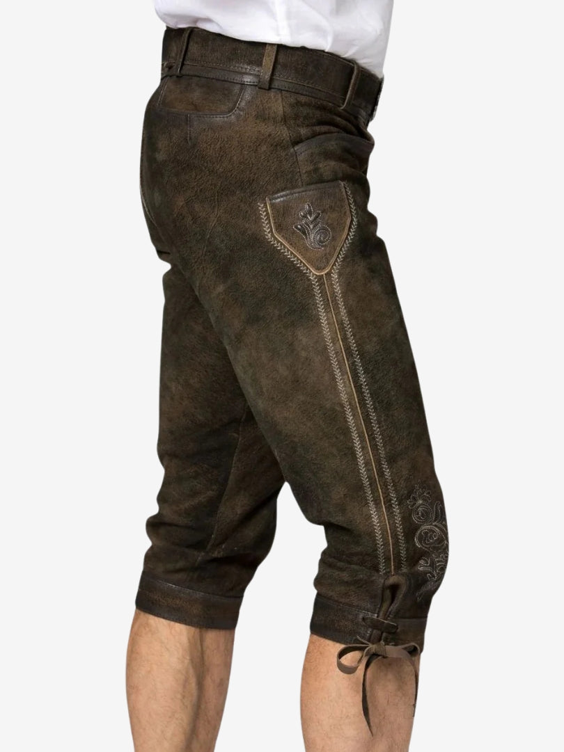 Side view of brown bundhosen showing decorative embroidery panel, pocket detail, and lace-up knee closures.