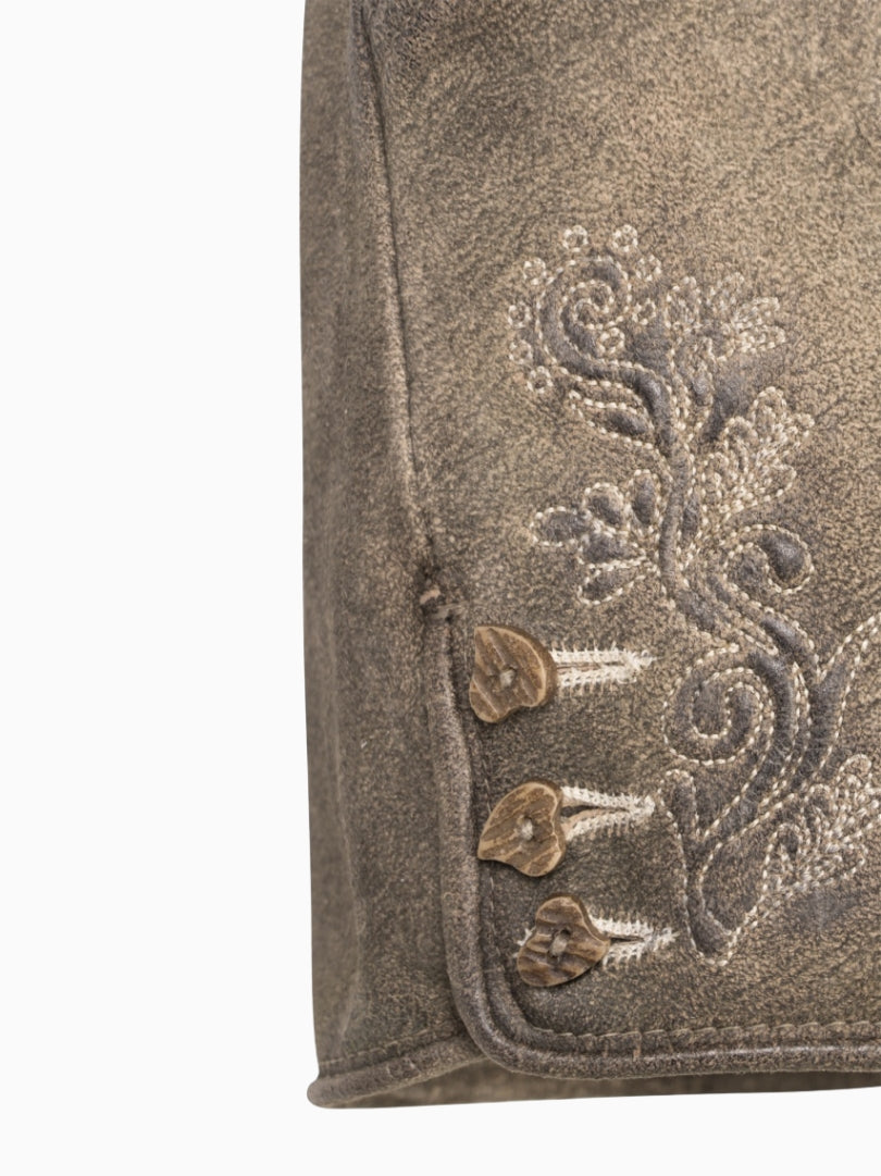 Close-up of a brown fabric with floral embroidery and buttons on a white background