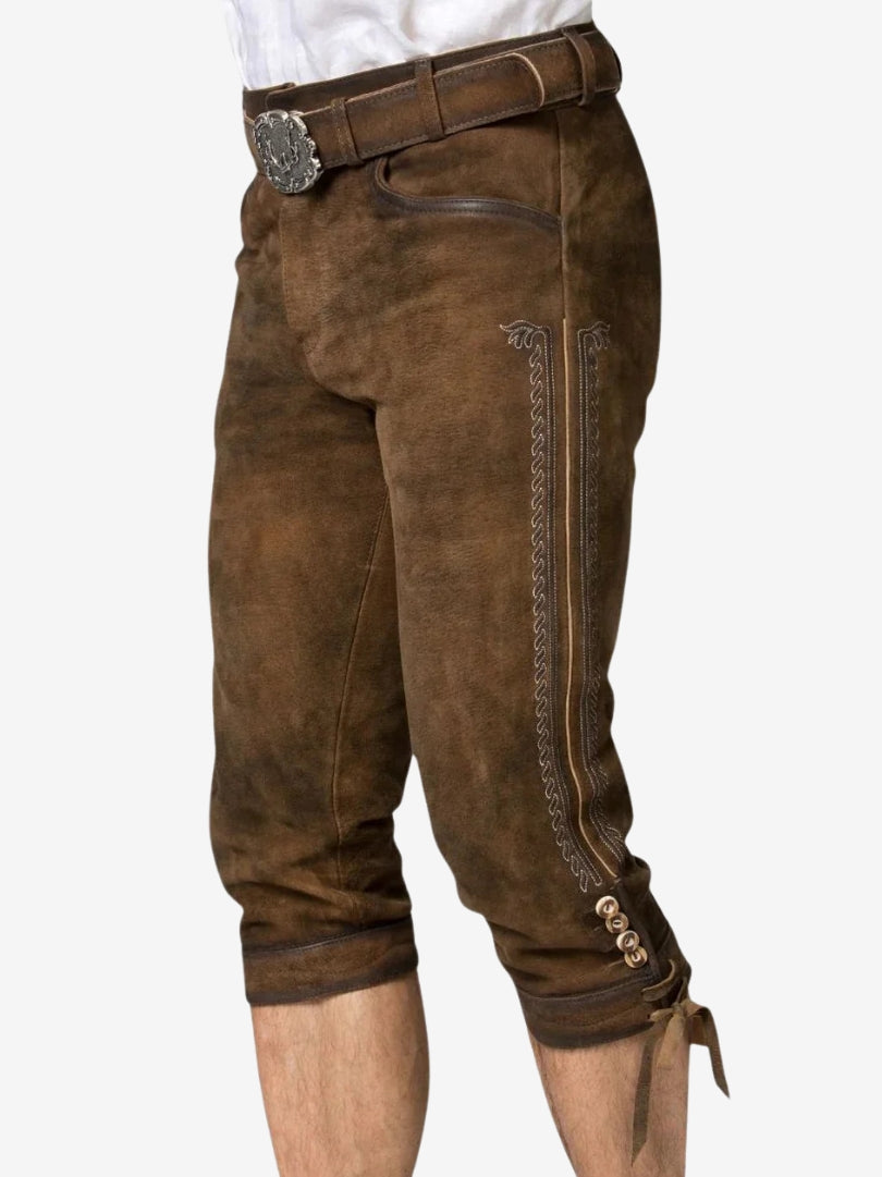 Angled front view of brown bundhosen showing side embroidery, buttons near the knee, and leather texture.