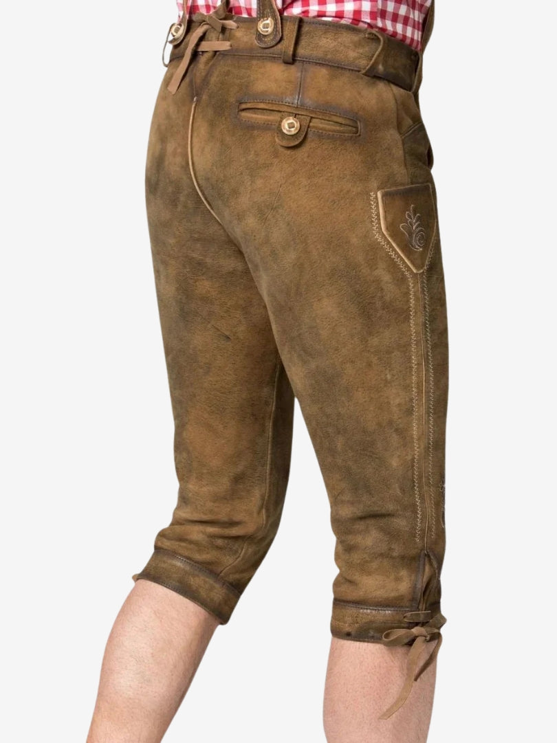 Angled back view of brown bundhosen showing side embroidery, rear pocket, and knee-length fit with tie closures.