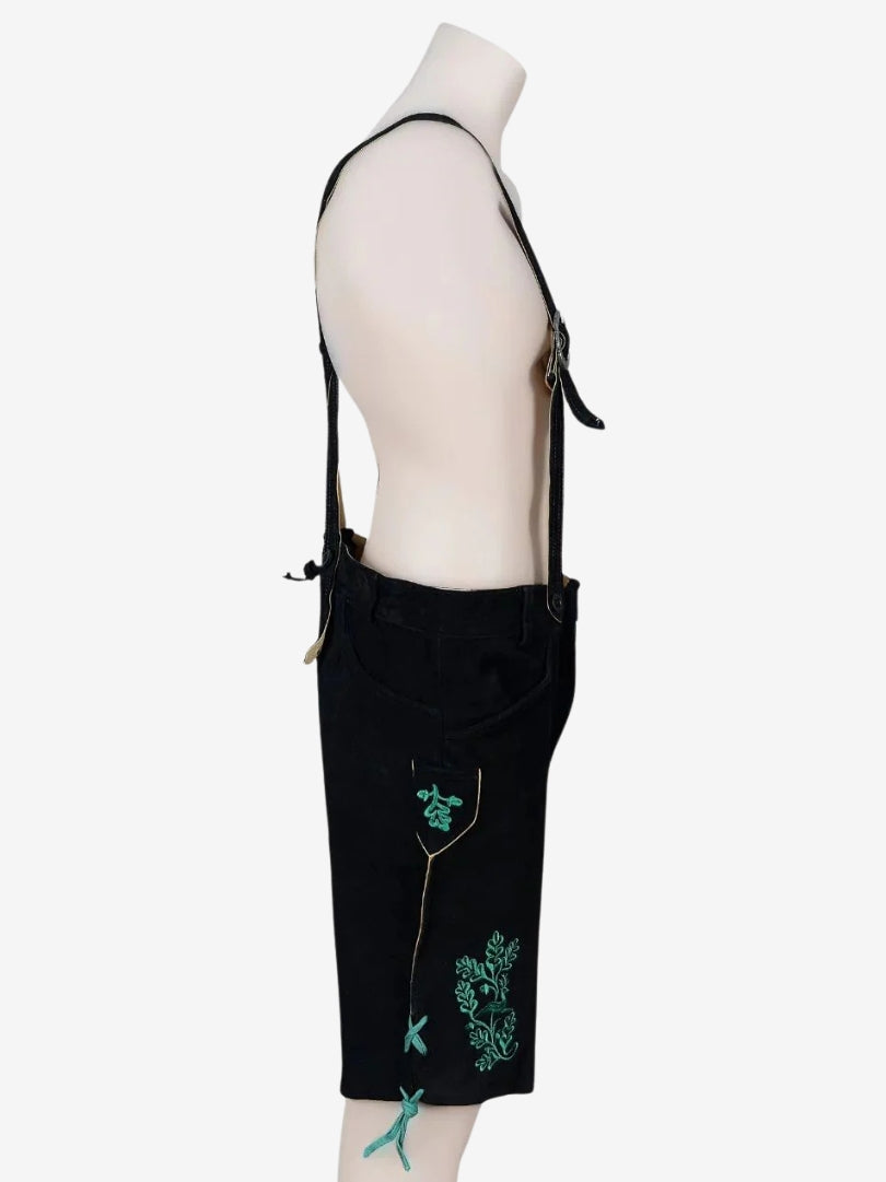 Opposite side view of black lederhosen showing pocket detail, embroidery, and suspenders attachment.