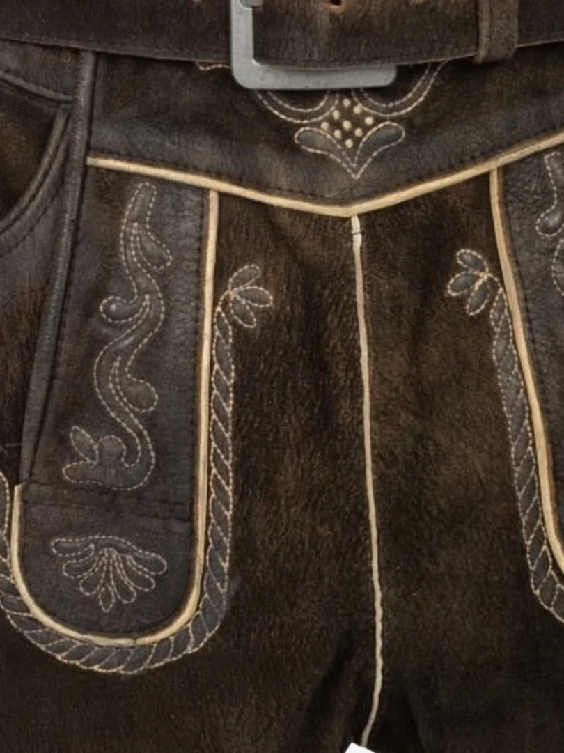 Close-up of lederhosen front flap highlighting fine embroidery, contrast piping, and textured leather.