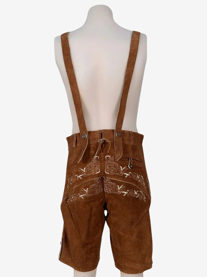 Back view of brown lederhosen with suspenders on a mannequin, featuring embroidered back panel and adjustable waistband.