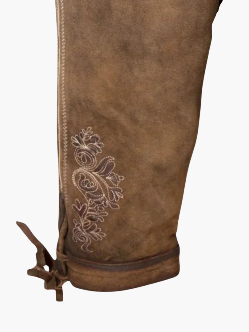 Close-up of brown bundhosen leg highlighting intricate white floral embroidery and side seam stitching with lace-up cuff.