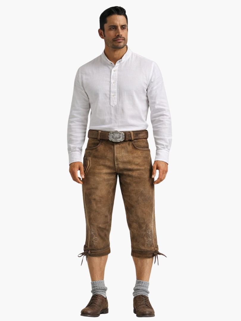 Man wearing brown suede bundhosen with white shirt, grey socks, and brown shoes, styled in traditional Oktoberfest outfit.