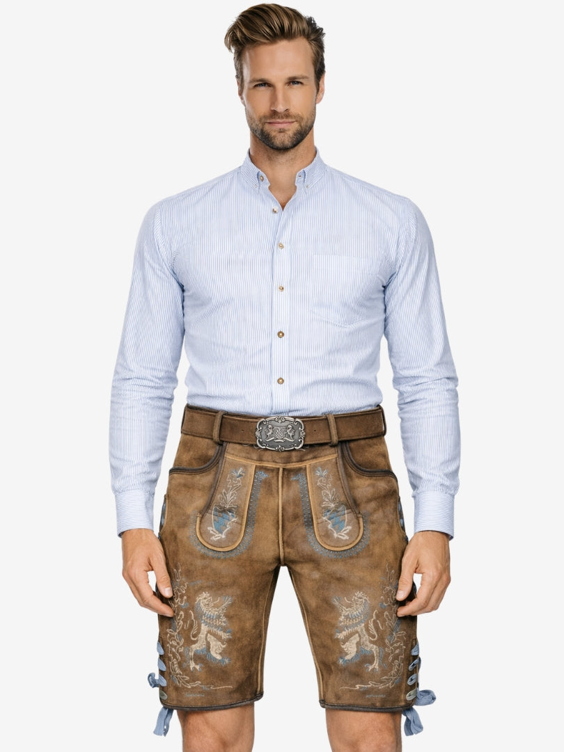 Man wearing brown lederhosen with blue embroidered lion patterns, paired with a light blue shirt and belt, in traditional Bavarian style.