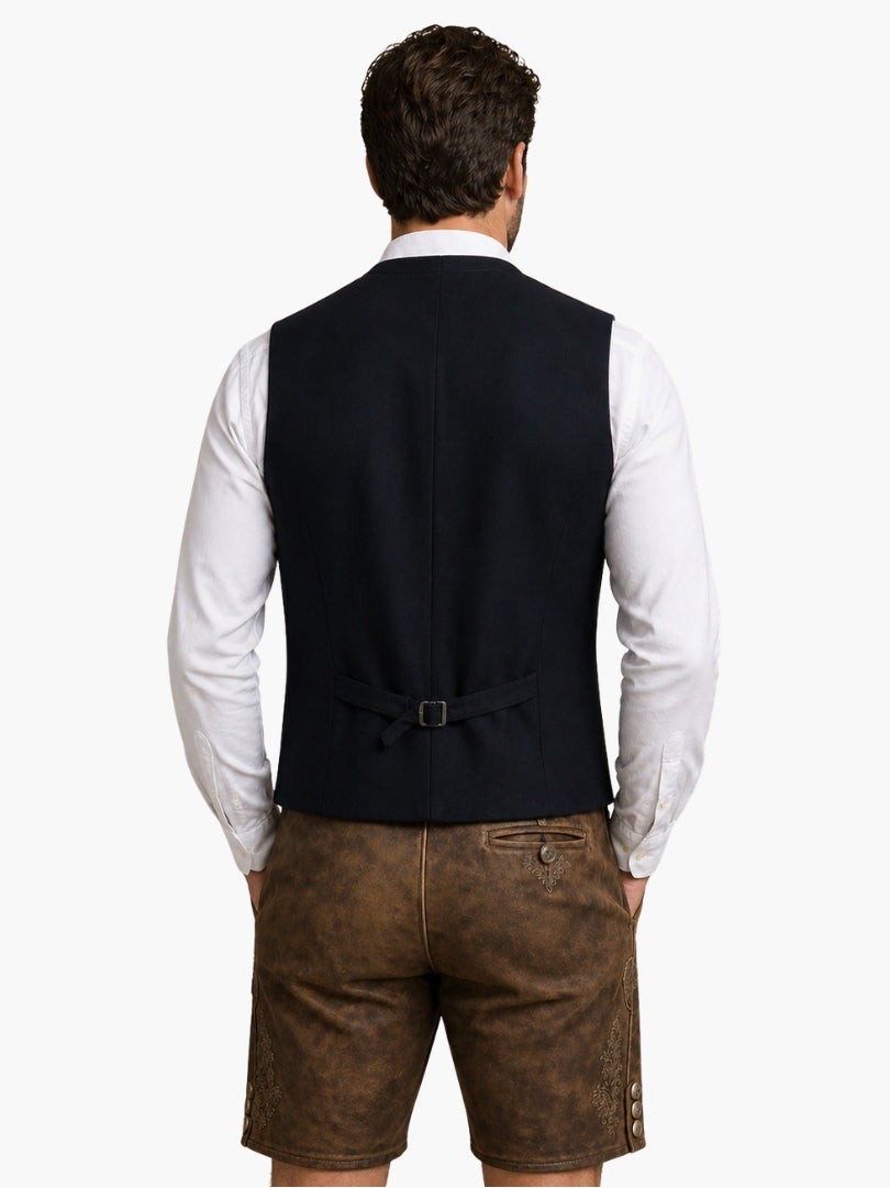 Men’s black Oktoberfest vest with traditional buttons, worn over white shirt and paired with leather lederhosen shorts.