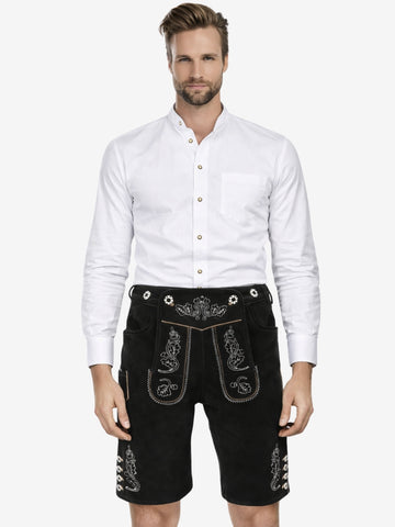 Man wearing a white button-up shirt paired with black embroidered lederhosen shorts, standing against a plain background.
