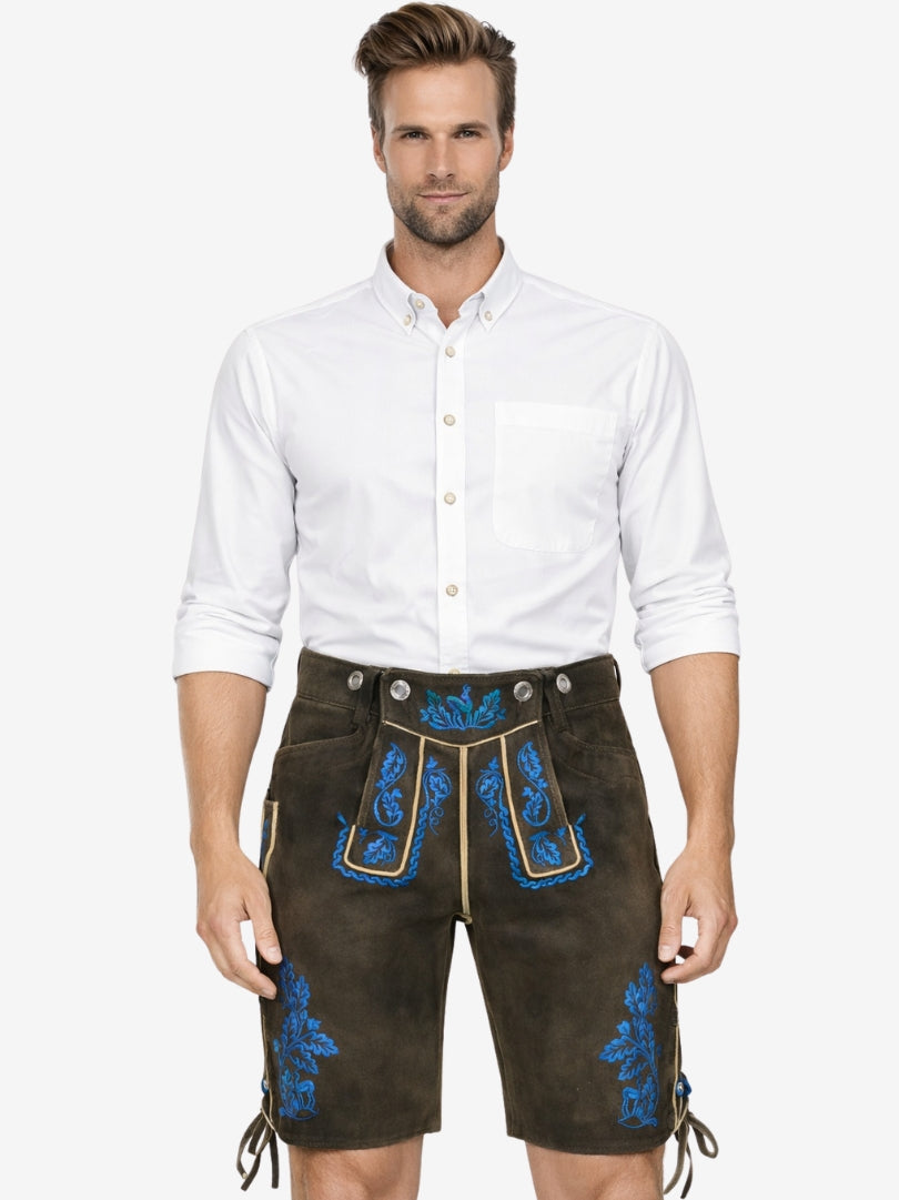 Man wearing dark brown lederhosen with vibrant blue embroidery paired with a white shirt in traditional Bavarian style.