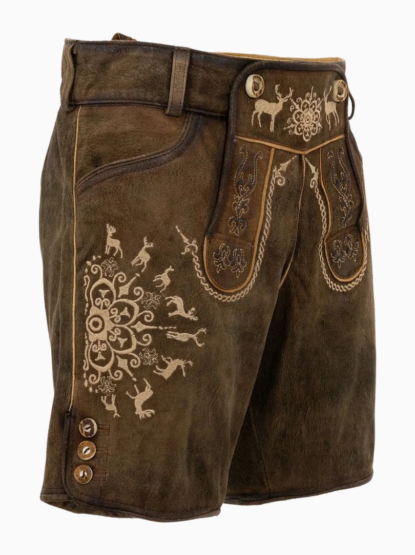 Close-up of a person wearing traditional brown Bavarian lederhosen made of leather, featuring decorative embroidery with deer and floral patterns, front flap detailing, and side buttons, paired with a light-colored shirt.