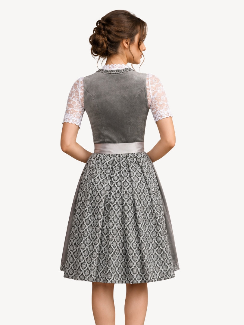 A woman shown from the back wearing a traditional German dirndl dress. The dress features a gray velvet bodice, white lace short sleeves, a light gray waistband, and a pleated gray and white patterned skirt.