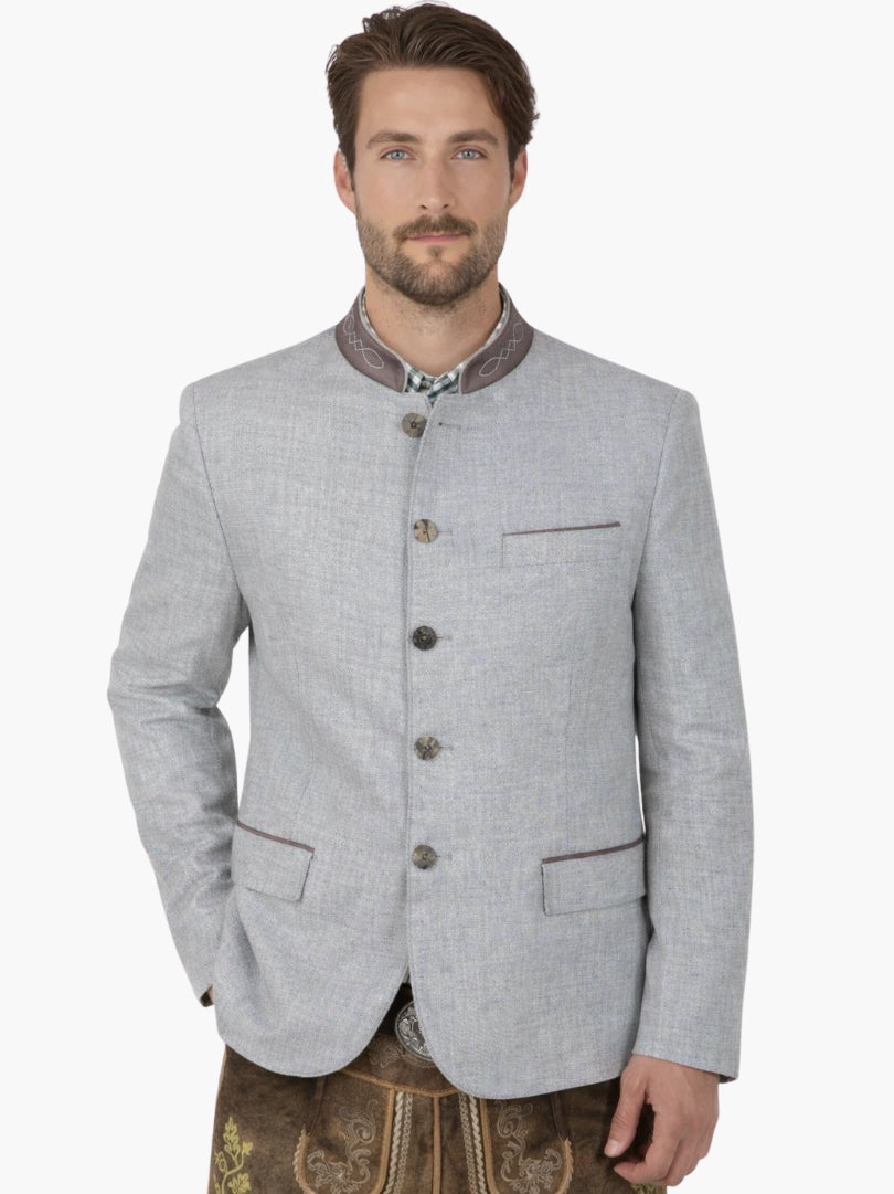 Man wearing a grey Trachten jacket paired with brown lederhosen, featuring classic Bavarian design, embroidered collar, and premium fabric.