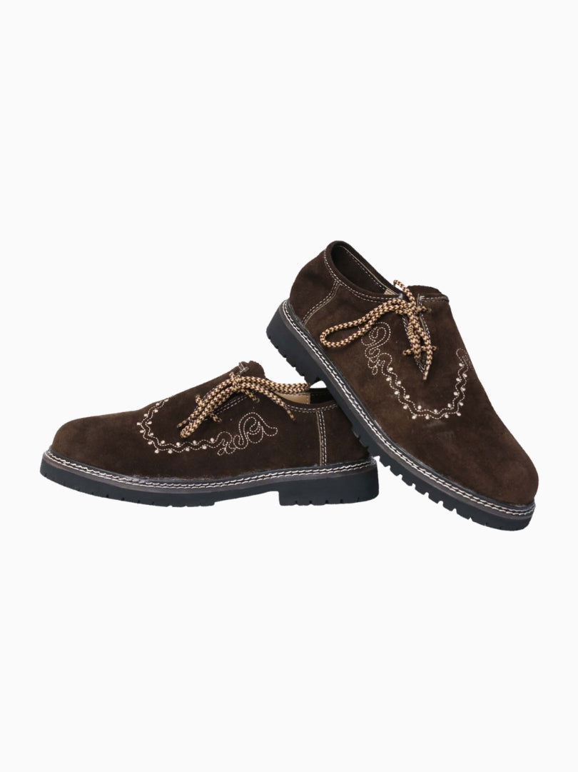 Pair of brown traditional Trachten shoes in suede leather with embroidered detail and thick black sole, displayed in angled side view.
