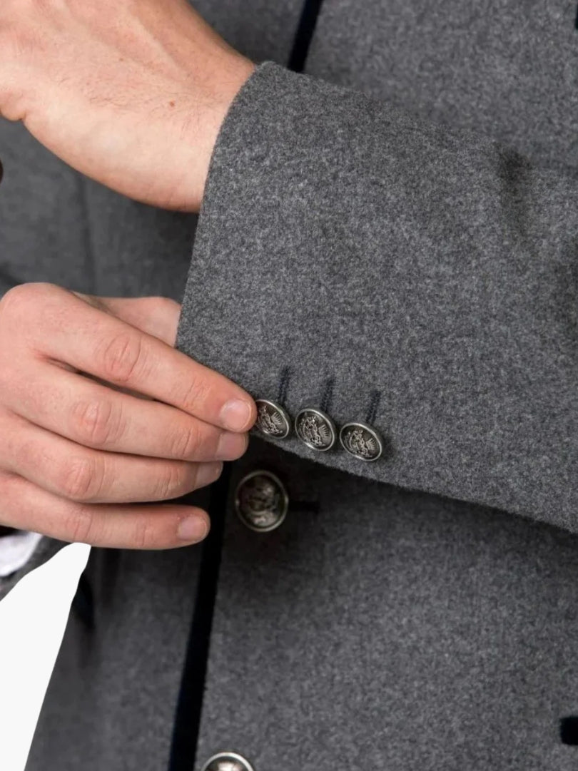 Close-up of grey Bavarian jacket sleeve featuring decorative metal buttons and premium wool texture.