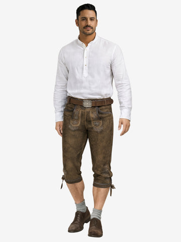 Man dressed in traditional brown bundhosen with white shirt, belt, socks, and shoes in a full-length front view.