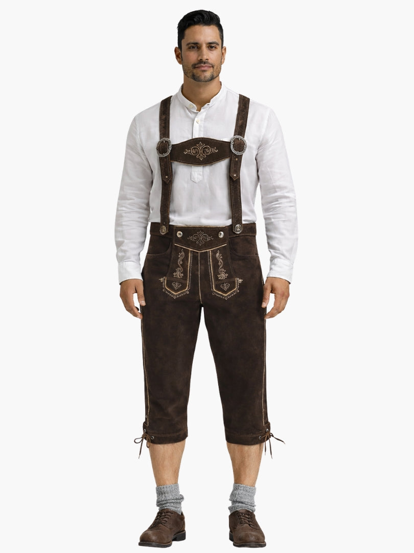 Man wearing brown leather bundhosen with suspenders, paired with a white shirt, grey socks, and brown shoes in a front-facing pose.
