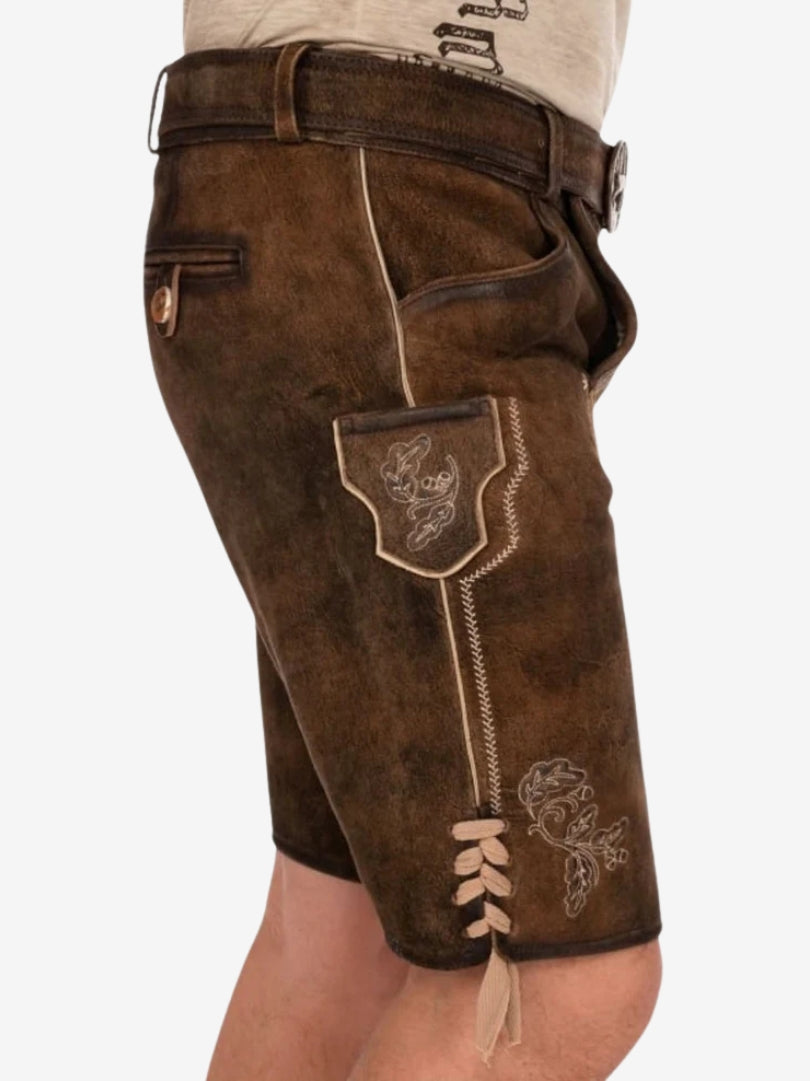 Side view of lederhosen showing stitched side pocket with embroidery, contrast piping, and lace-up accents near the hem.