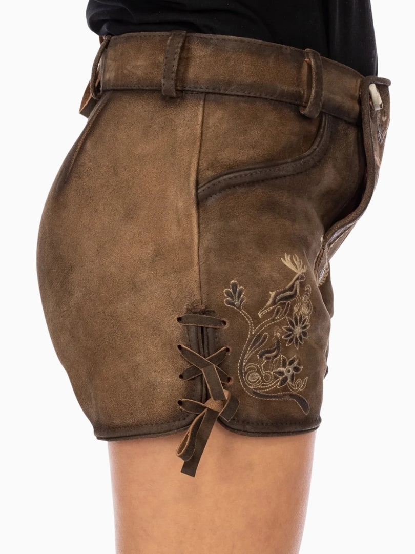 Front view of dark brown traditional lederhosen-style shorts with embroidered patterns, decorative front flap with buttons, and side lace details, worn with a black top.