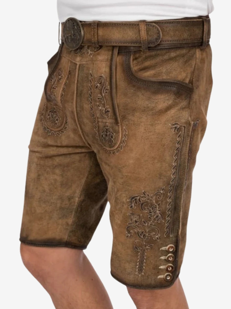 Angled view of tan lederhosen highlighting embroidered patterns, front flap design, and side button detailing.