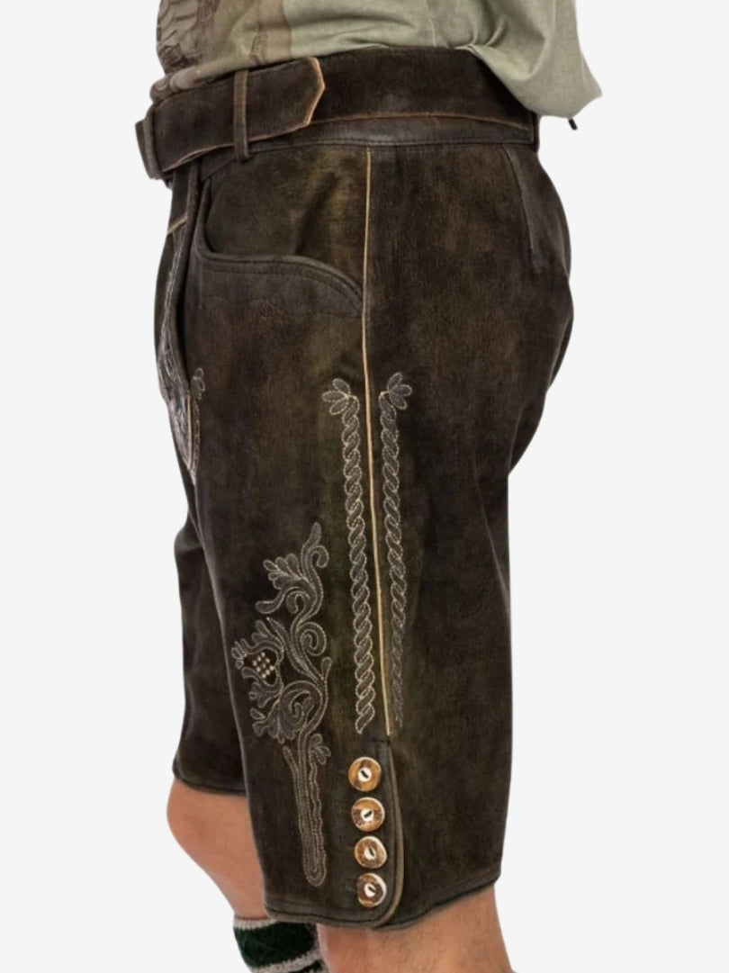 Side angle of dark brown lederhosen showing embroidered patterns, vertical stitching, and button accents along the hem.