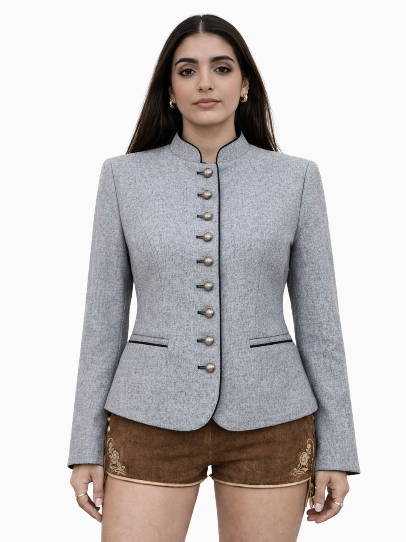 Womens light grey Bavarian Trachten jacket with traditional button front, tailored fit, and black piping detail, paired with brown embroidered lederhosen shorts.