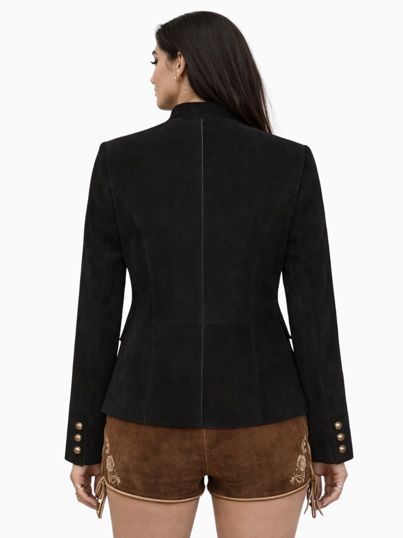 Rear view of a womens black traditional Trachten jacket showcasing a fitted silhouette, clean tailored seams, and long sleeves with button details, worn with embroidered brown lederhosen shorts for an authentic Bavarian look.