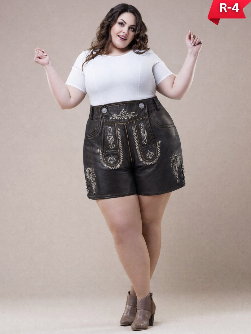 Women’s plus size lederhosen in black leather with traditional Bavarian embroidery, worn with a white top and ankle boots, full-length studio image.