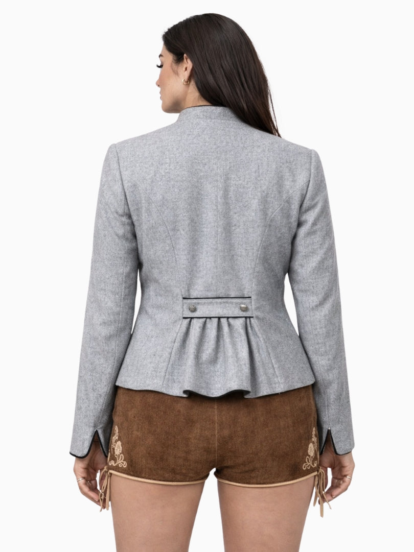Womens light grey Bavarian Trachten jacket with traditional button front, tailored fit, and black piping detail, paired with brown embroidered lederhosen shorts.