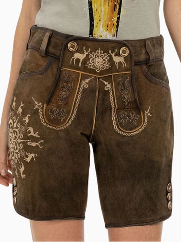 Close-up of a person wearing traditional brown Bavarian lederhosen made of leather, featuring decorative embroidery with deer and floral patterns, front flap detailing, and side buttons, paired with a light-colored shirt.