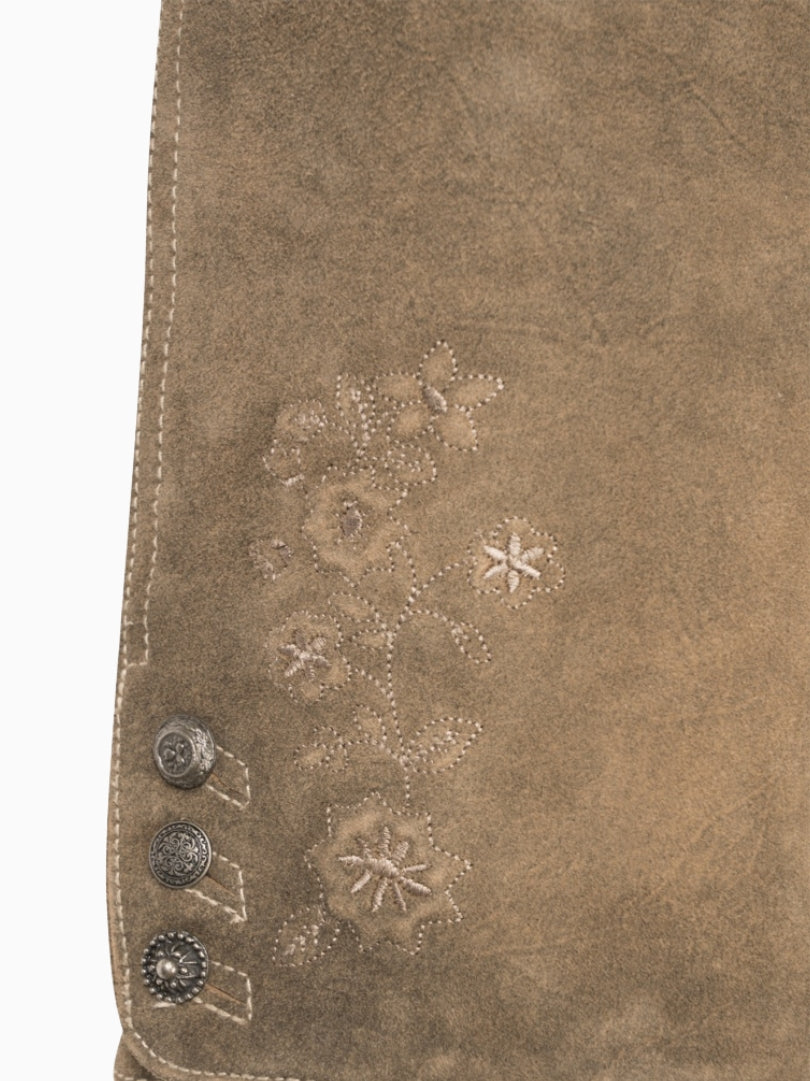 Close-up of a brown leather bag with floral embroidery and metal studs.
