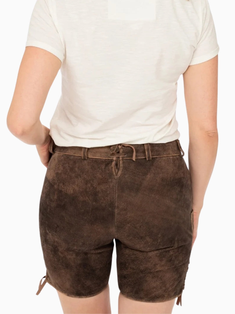 Back view of dark brown traditional lederhosen style shorts featuring an adjustable back lace detail, belt loops, and a worn leather finish, worn with a white top.