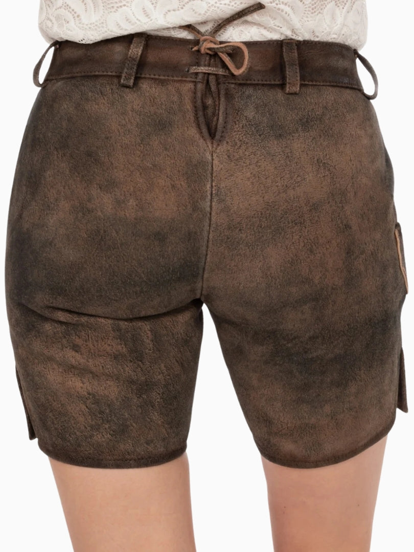 Back view of dark brown traditional lederhosen-style shorts with an adjustable back lace detail, belt loops, and a rustic distressed leather texture, worn with a white lace top.
