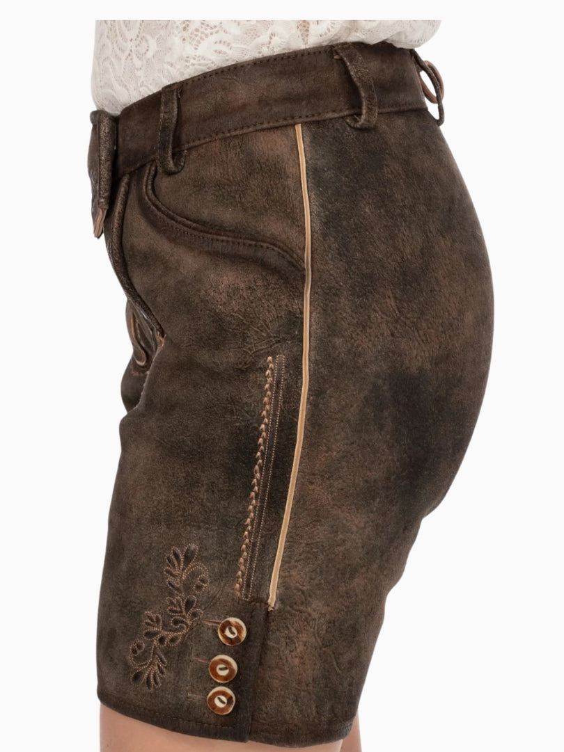 Side view of dark brown traditional lederhosen-style shorts with embroidered floral detailing, contrast piping, and decorative buttons near the hem, showing a textured leather finish.